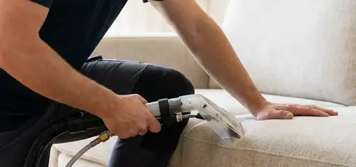 Professional upholstery cleaner deep-cleaning a fabric sofa with a handheld extraction tool, Dover, DE.